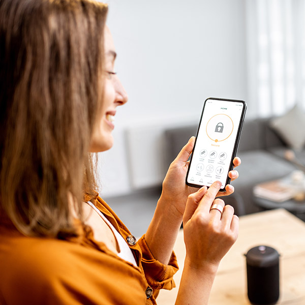 Woman holding smart phone with launched security application at home